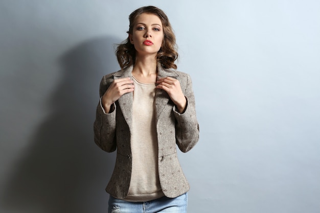 Photo portrait of beautiful model in jeans and jacket on gray