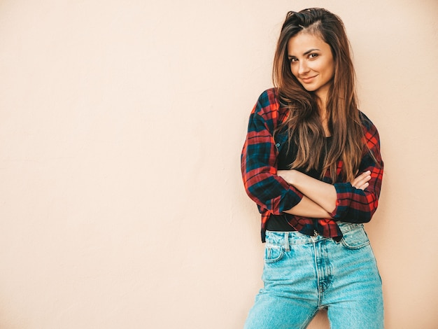 Foto ritratto di bella modella. donna sexy vestita in jeans e camicia a scacchi hipster estivi. ragazza alla moda in posa vicino al muro in strada