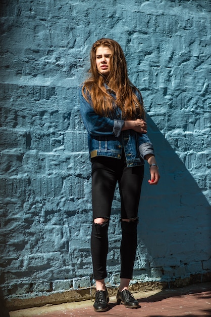 Portrait of a beautiful modern girl against blue brick background