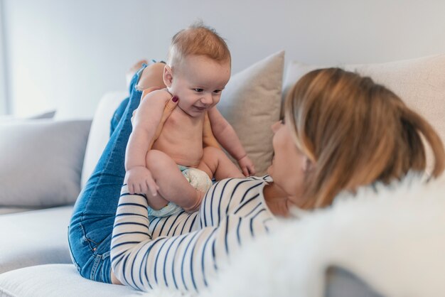 Portrait of beautiful mom playing with her baby in bedroom