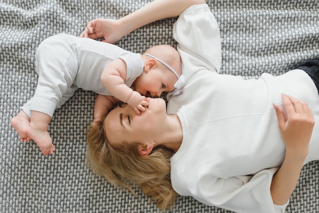 Ritratto di bella mamma che gioca con il suo bambino di quattro mesi nella vista dall'alto della camera da letto