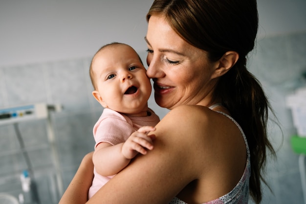 Portrait of beautiful mother with her baby in the hospital background. Healthcare and medical family love lifestyle concept