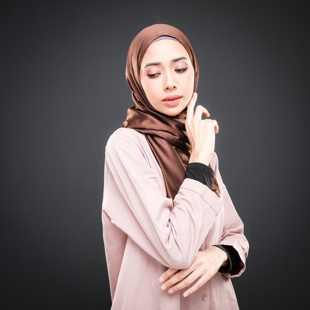 Portrait of a beautiful Muslim female model wearing modern casualwear with hijab isolated on dark