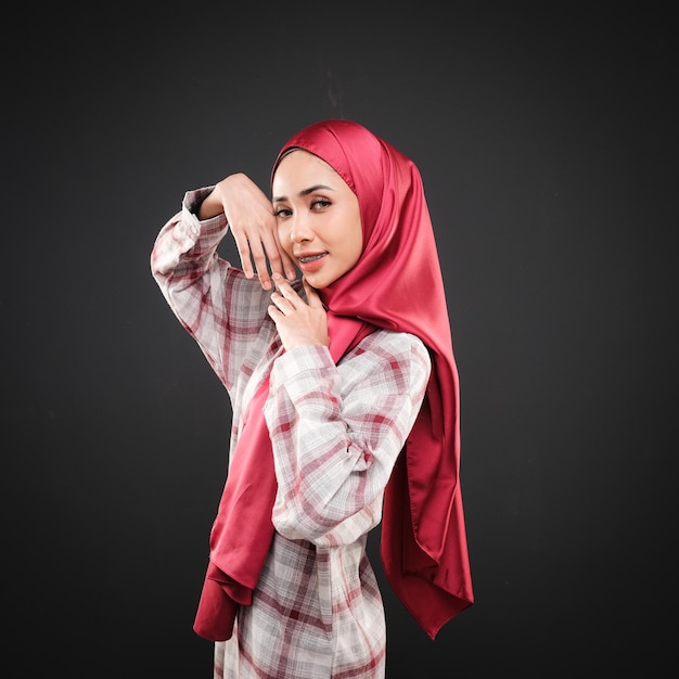 Portrait of a beautiful Muslim female model wearing modern casualwear with hijab isolated on dark