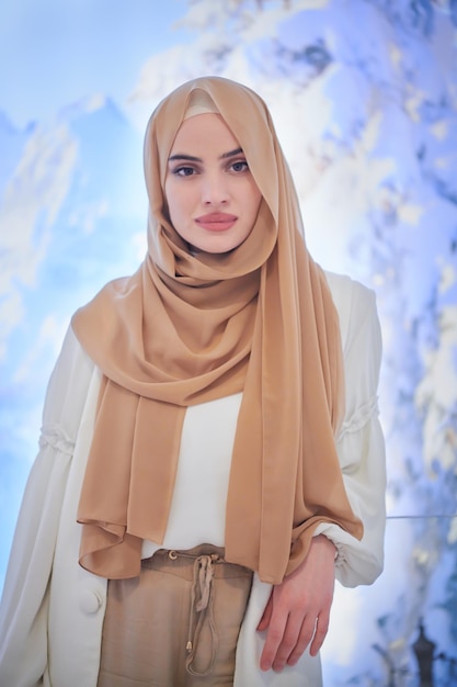 portrait of beautiful muslim woman in fashionable dress with hijab isolated on modern winter mountains background representing modern islam fashion and ramadan kareem concept