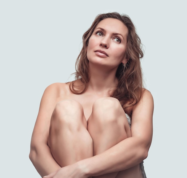 Photo portrait of a beautiful nude woman sitting with her knees tightened