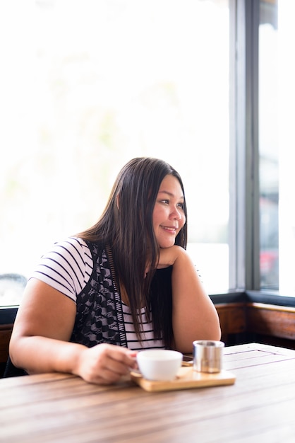 Portrait of beautiful overweight Asian woman relaxing at the coffee shop