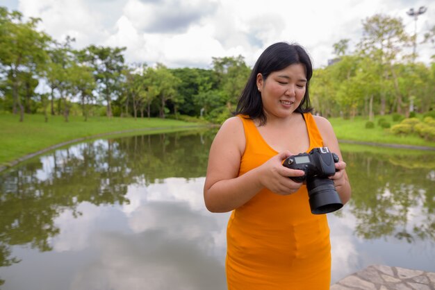 Portrait of beautiful overweight Asian woman relaxing at the park in the city of Bangkok, Thailand