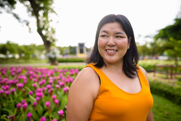 Portrait of beautiful overweight Asian woman relaxing at the park in the city of Bangkok, Thailand