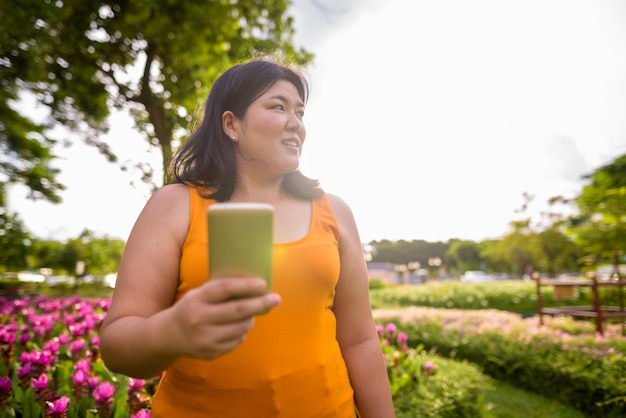 Portrait of beautiful overweight Asian woman relaxing at the park in the city of Bangkok, Thailand