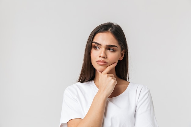 Portrait of a beautiful pensive young woman casualy dressed standing isolated on white