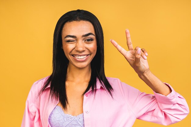 Portrait of beautiful positive african american black woman standing isolated over yellow background