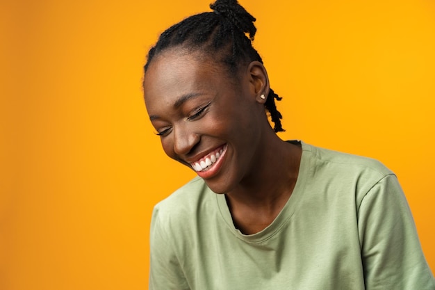 노란색 스튜디오에서 아름다운 긍정적인 아프리카계 미국인 여성의 초상화