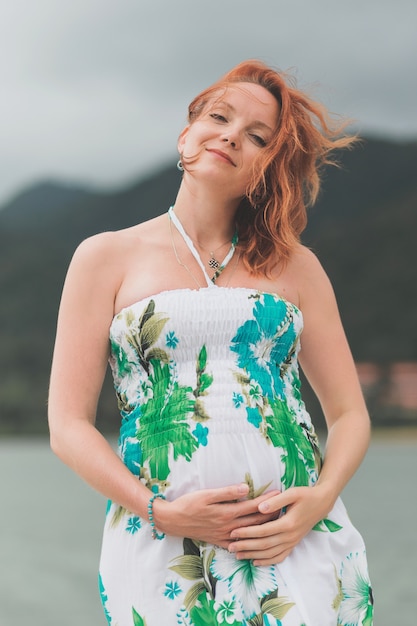 A portrait of a beautiful pregnant woman smile brightly in colorful dress on the beach