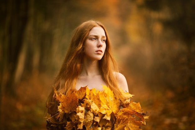 Portrait of beautiful red haired Woman, Fall Leaves Dress in the autumn park