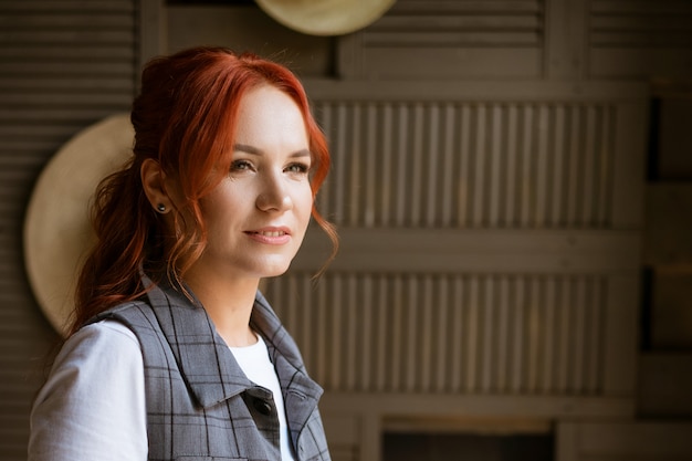 Photo portrait of a beautiful red haired woman looking towards the window