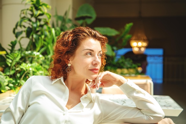 Portrait of a beautiful redhaired fashionable woman in a cafe