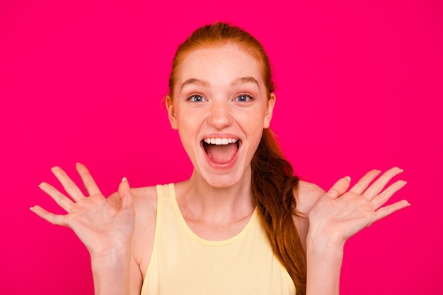 Portrait beautiful redhead girl isolated over pink wall