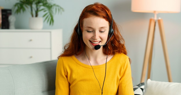 Portrait of beautiful redhead girl with headsets using laptop