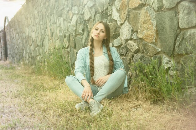 Ritratto di una bellissima giovane donna romantica in campagna al tramonto. ragazza attraente in vestiti di jeans