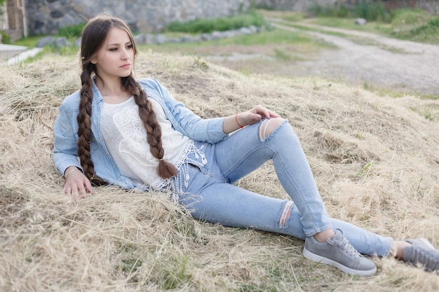 日没時の田舎の美しいロマンチックな若い女性の肖像画。デニムの服を着た魅力的な女の子