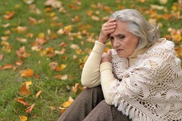 Foto ritratto di una bella donna anziana triste sullo sfondo sfocato dell'autunno