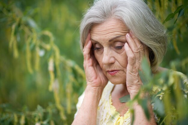 Portrait of beautiful sad senior woman in summer park