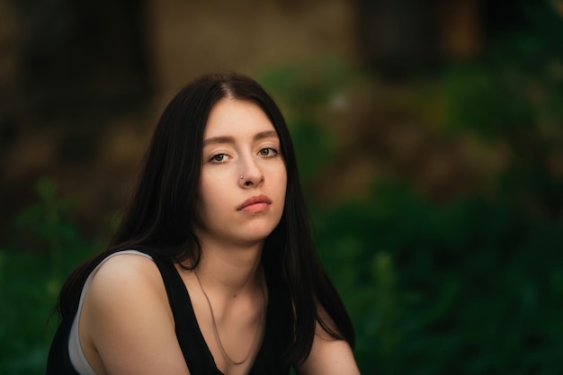 portrait of a beautiful sad young girl on a background of greenery