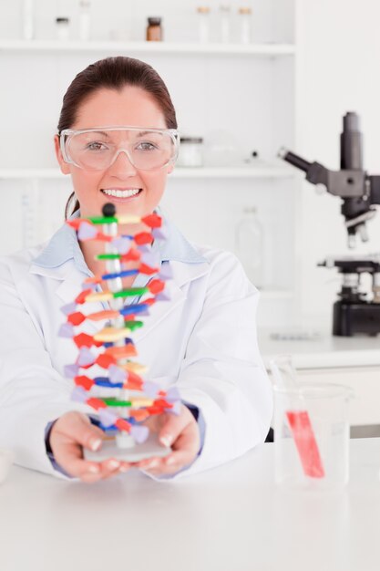 Portrait of a beautiful scientist showing the dna double helix model