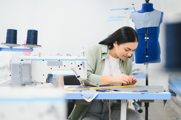 Portrait of a beautiful seamstress carrying a tape measure and working in a textile factory