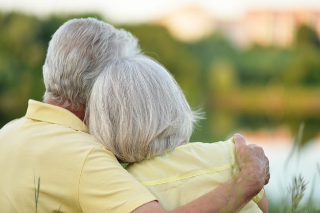 Portrait of beautiful senior couple hugging in the park back view