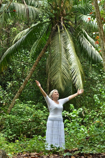 Портрет красивой пожилой женщины на открытом воздухе в тропическом парке