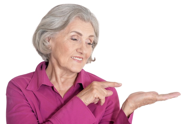 Portrait of beautiful senior woman pointing to the right on white background