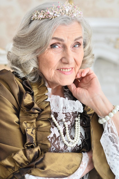 Portrait of beautiful senior woman Queen posing indoors