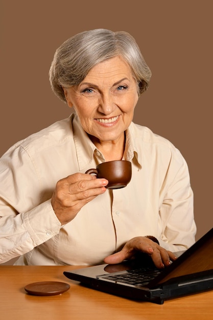 Портрет красивой пожилой женщины, сидящей за столом