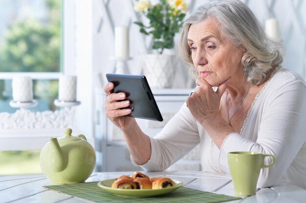 Портрет красивой пожилой женщины с планшетным ПК дома