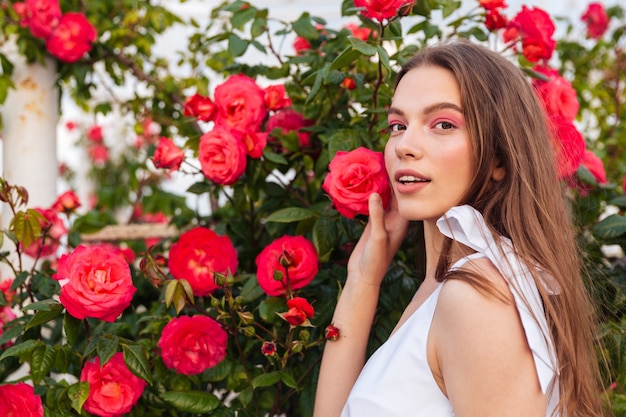 Portrait of a beautiful sensual young woman over flowers background looking at camera