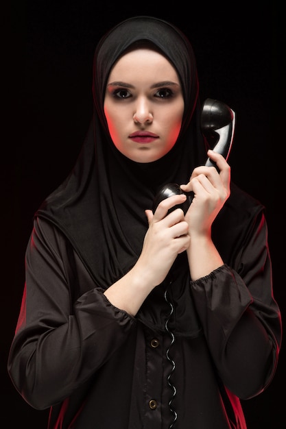 Portrait of beautiful serious scared young muslim woman wearing black hijab 