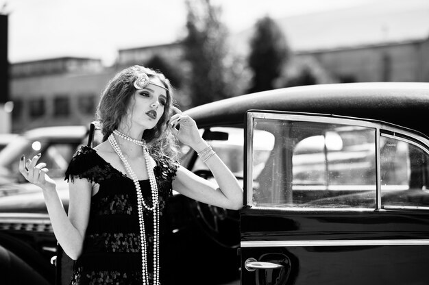 Portrait of beautiful sexy curly fashion girl model with bright makeup in retro style near vintage car 