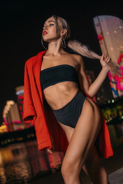 portrait of a beautiful and sexy girl in a black swimsuit on a night city