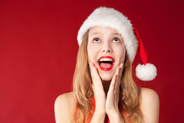 Portrait of beautiful sexy girl wearing santa claus clothes over red background