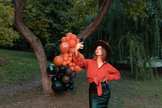 Portrait of beautiful sexy young woman in witch halloween costume with orange and black balloons