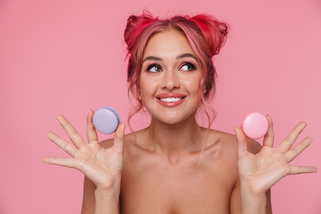 Portrait of beautiful shirtless young woman with colorful hairstyle holding macaron cookies