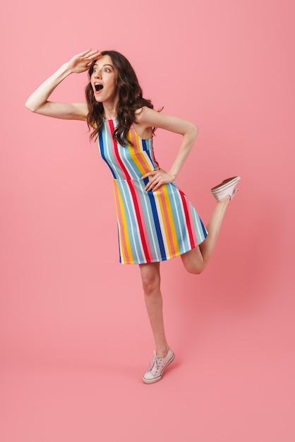 Portrait of beautiful shocked young cute woman posing isolated over pink wall looking aside