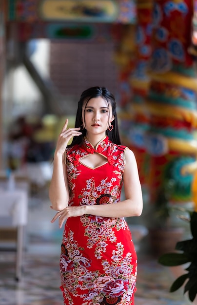 Фото Портрет красивой улыбки азиатская молодая женщина в красном платье чонсам традиционное украшение для китайского новогоднего фестиваля празднует культуру китая в китайском храме в таиланде