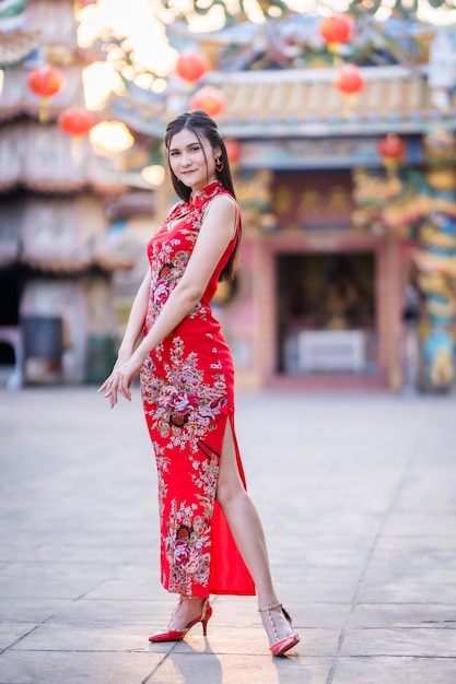 Портрет красивой улыбающейся азиатской молодой женщины в красном традиционном китайском чонсаме на фестивале китайского Нового года в китайском храме