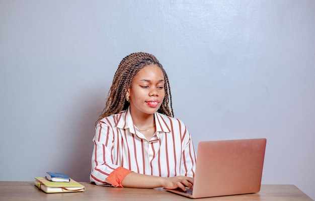 Portrait of a beautiful smiling African woman sitting at a desk using computer