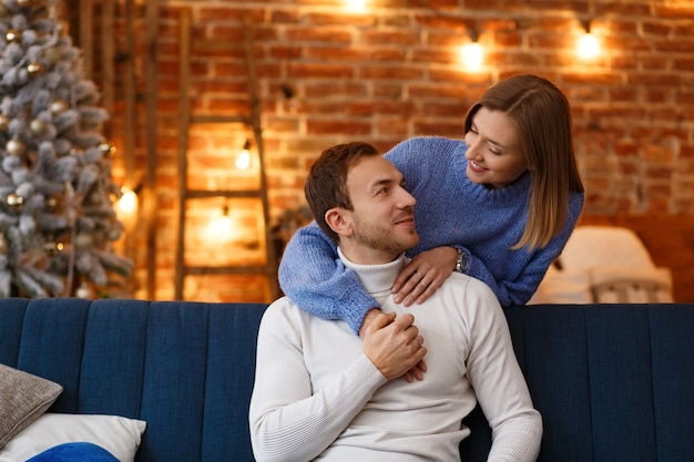 Portrait of beautiful smiling couple hugging at Christmas eve. Beautiful young couple at home enjoying spending time together. Winter holidays, Christmas celebrations, New Year concept.