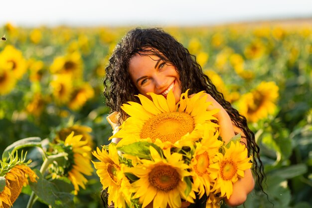 Portrait of a beautiful smiling dark-haired woman with bouquet of sunflowers