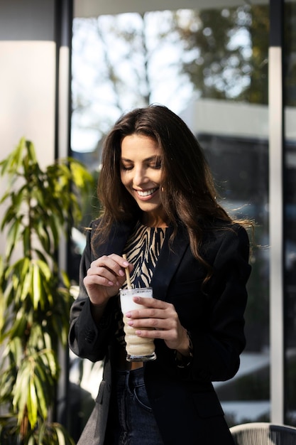 Ritratto di una bella ragazza sorridente in possesso di una tazza con una bevanda di caffè nelle sue mani una giovane donna in un caffè